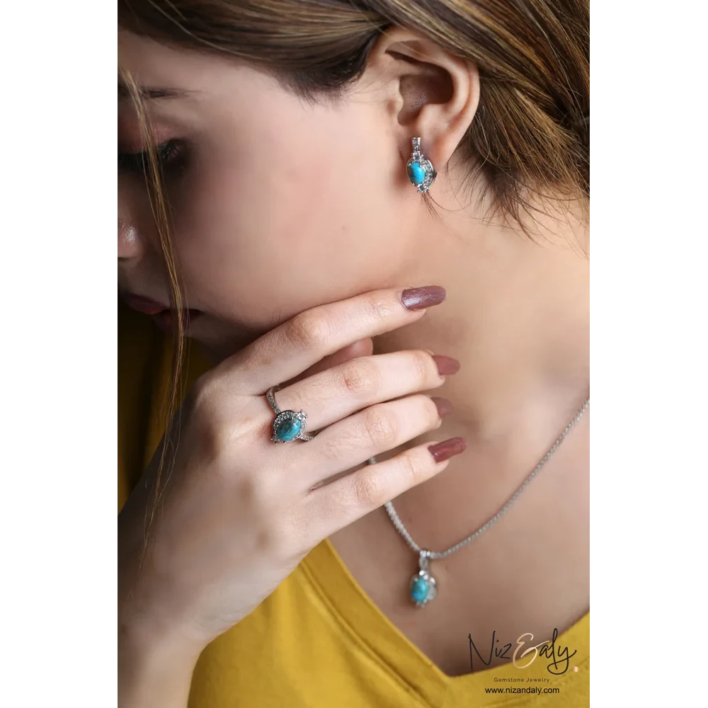 Niz & Aly oval Kingman blue turquoise pendant, stud earrings, and ring set in 925 sterling silver worn by a woman.