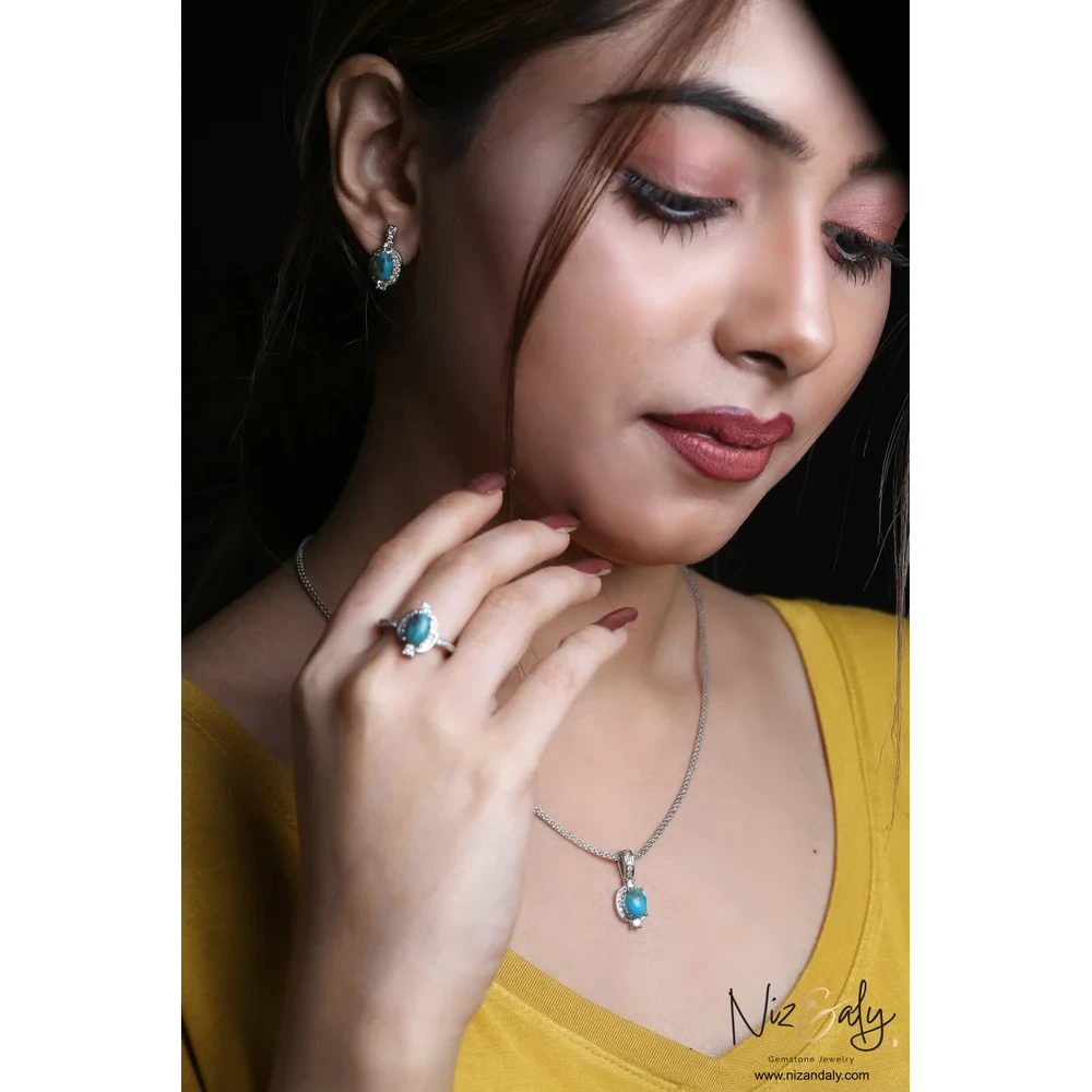 Niz & Aly oval Kingman blue turquoise pendant, ring, and stud earring set in 925 sterling silver worn by a woman.