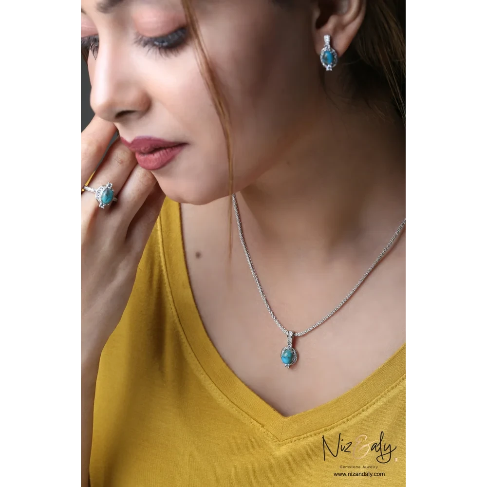 Niz & Aly oval Kingman blue turquoise pendant, stud earrings, and ring set in 925 sterling silver worn by a model.