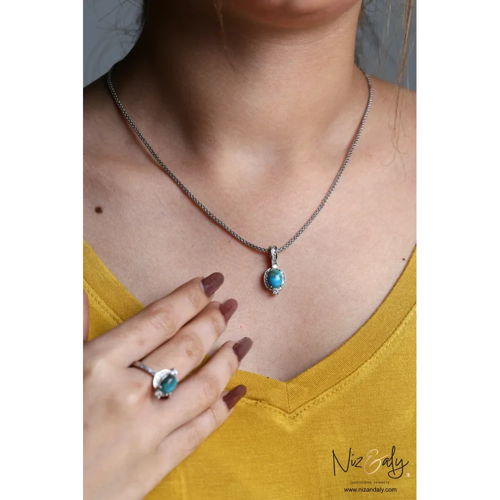 Niz & Aly oval Kingman blue turquoise pendant and ring set in 925 sterling silver worn by a woman in a yellow top