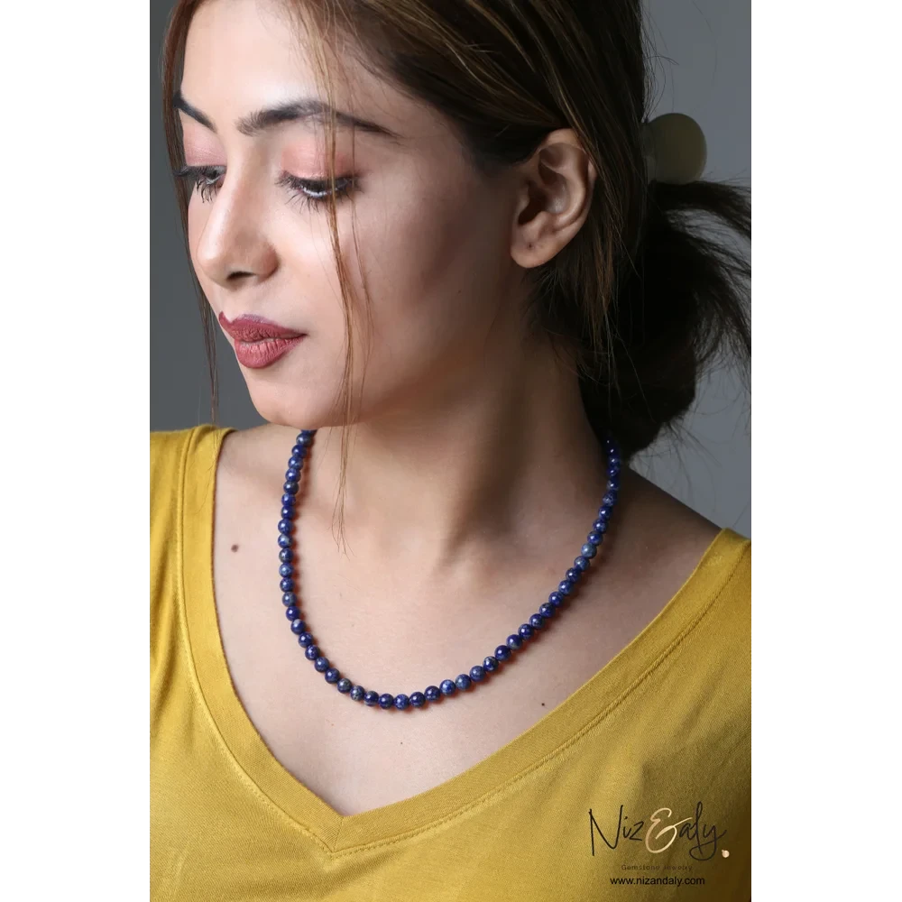 Niz & Aly Midnight Link necklace featuring deep blue lapis lazuli beads worn by a woman in a yellow top