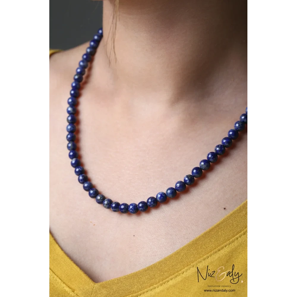 Niz & Aly Midnight Link necklace featuring deep blue lapis lazuli beads on a model wearing a yellow top.