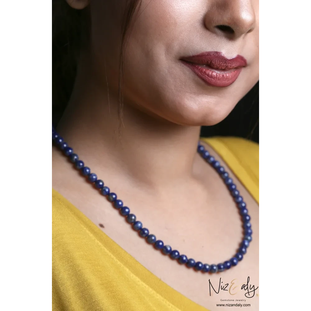 Niz & Aly Midnight Link necklace featuring deep blue lapis lazuli beads worn by a woman in a yellow top
