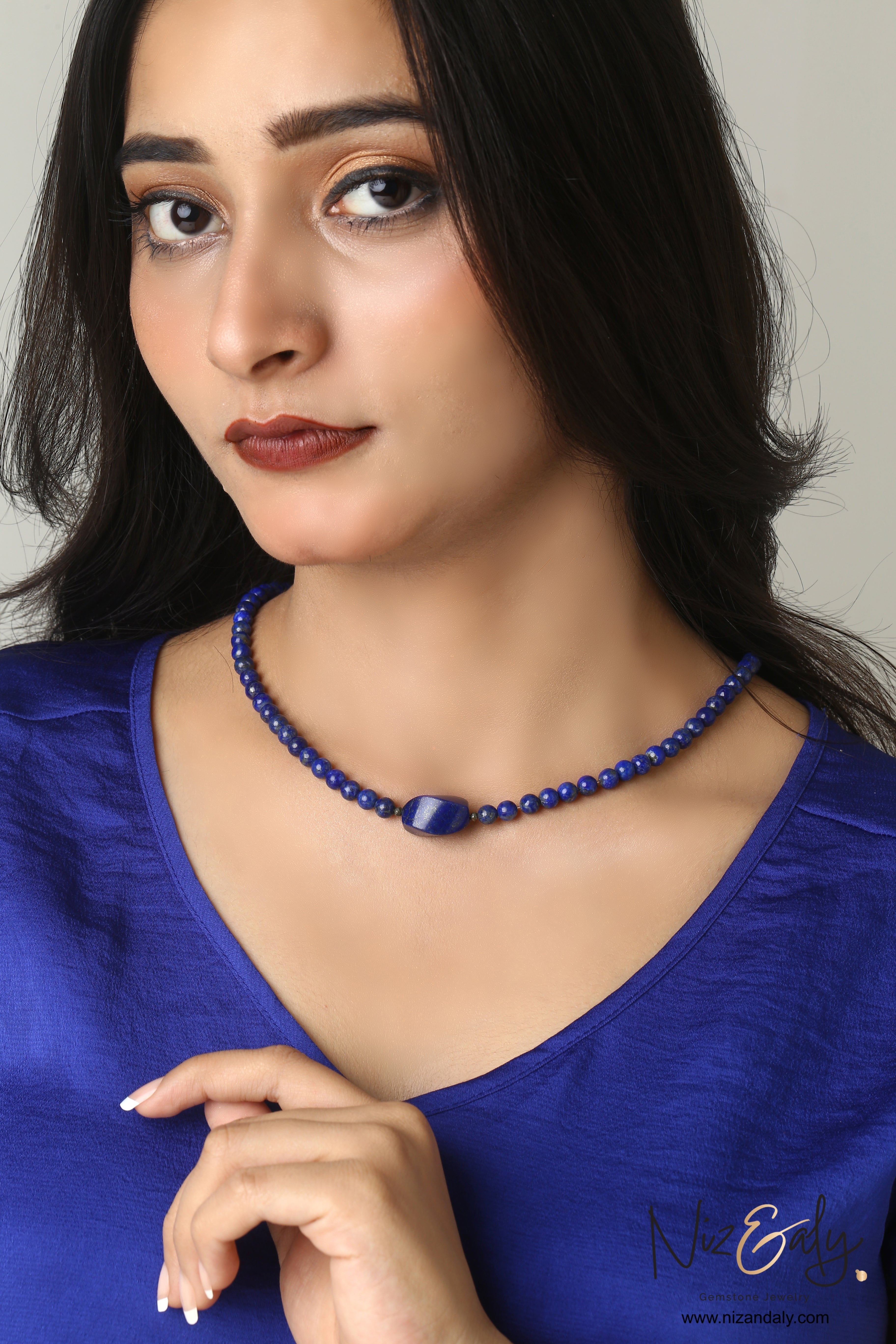 Niz & Aly Lapis Lazuli beaded necklace with a central gemstone worn by a woman in a blue top.