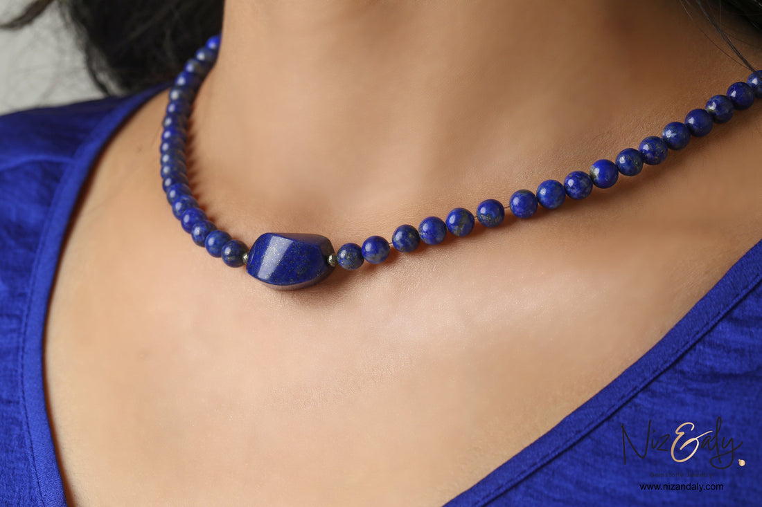 Niz & Aly Lapis Lazuli beaded necklace featuring a central polished gemstone on a woman wearing a blue top.