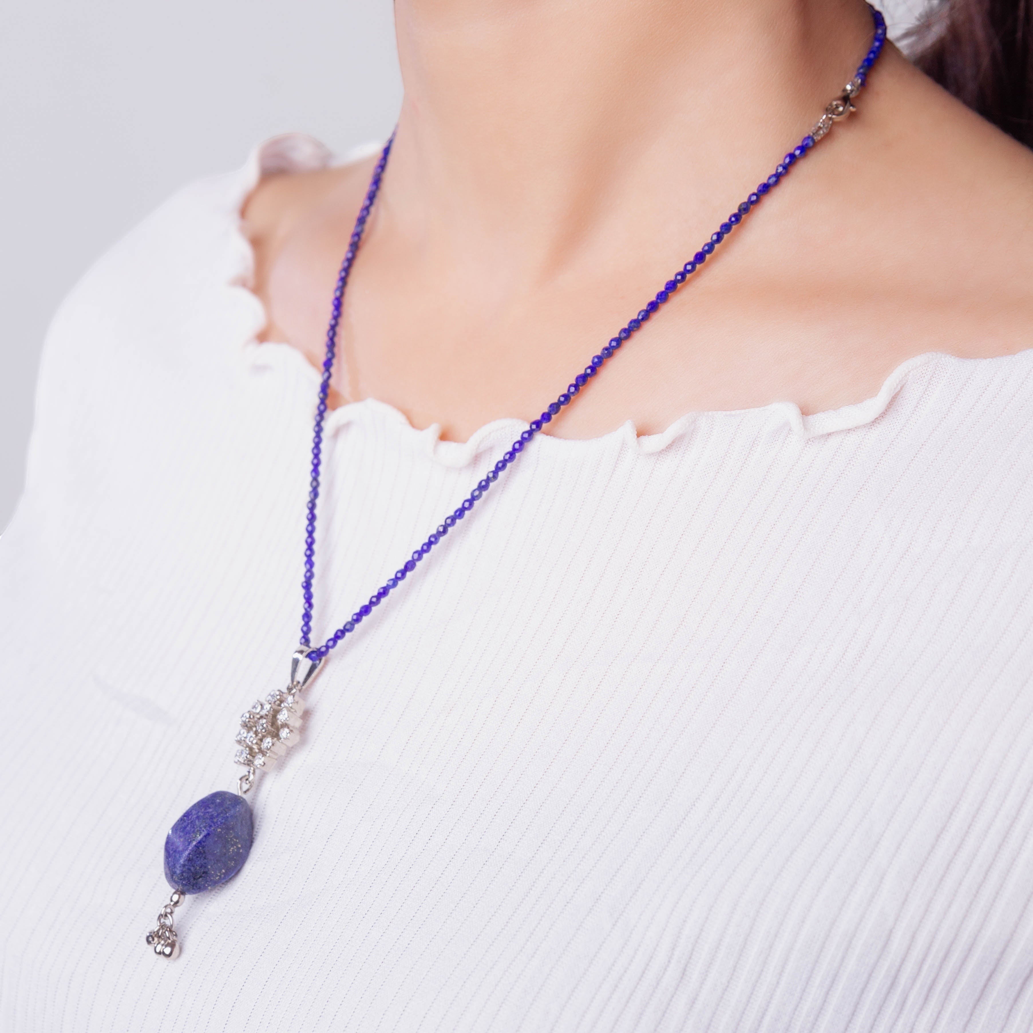Niz & Aly lapis lazuli pendant on a delicate blue beaded string worn by a woman in a white ribbed top