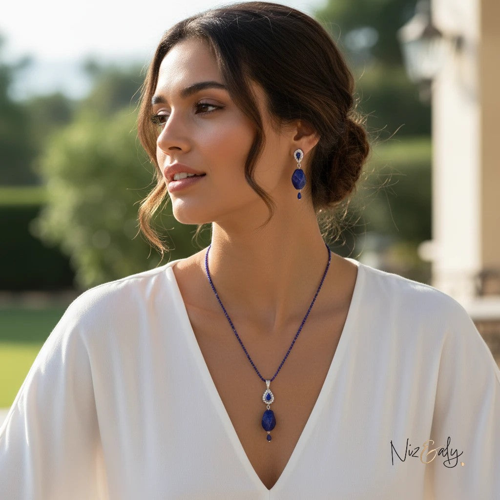 Niz & Aly tear drop lapis lazuli pendant necklace and matching earrings worn by a woman in a white blouse