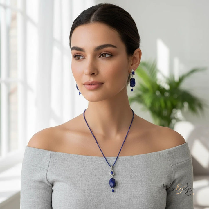 Niz & Aly tear drop lapis lazuli pendant necklace and matching earrings worn by a woman in a grey off-shoulder top.