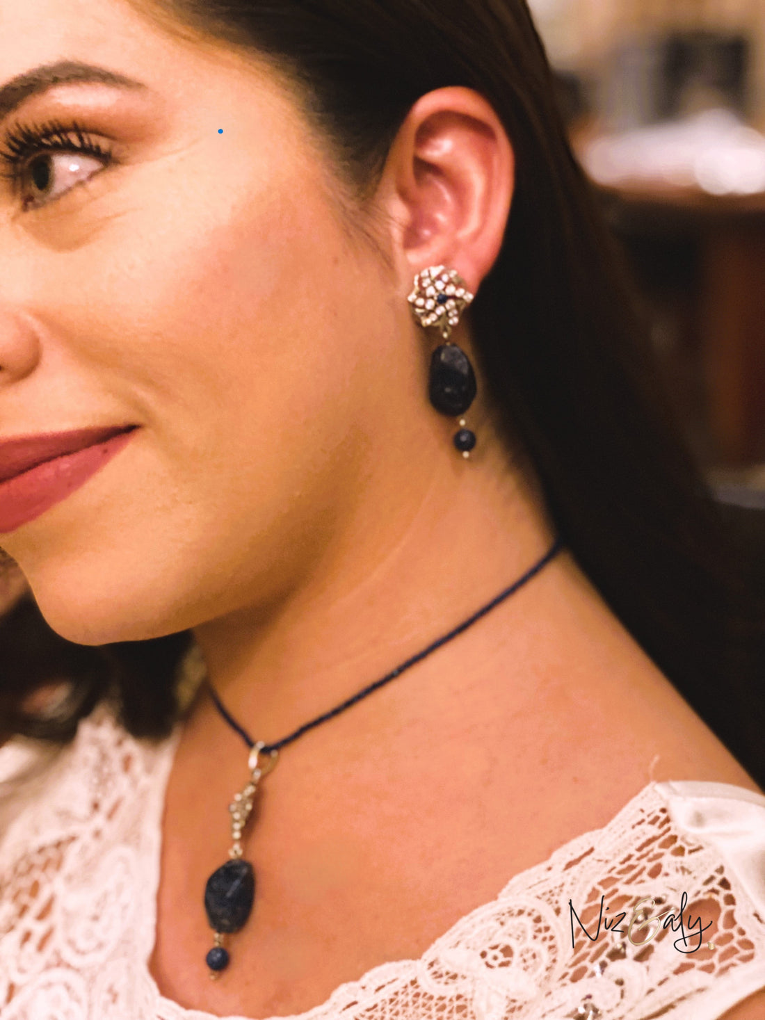 Niz & Aly lapis locket on a delicate faceted blue bead string worn by a woman with matching lapis drop earrings