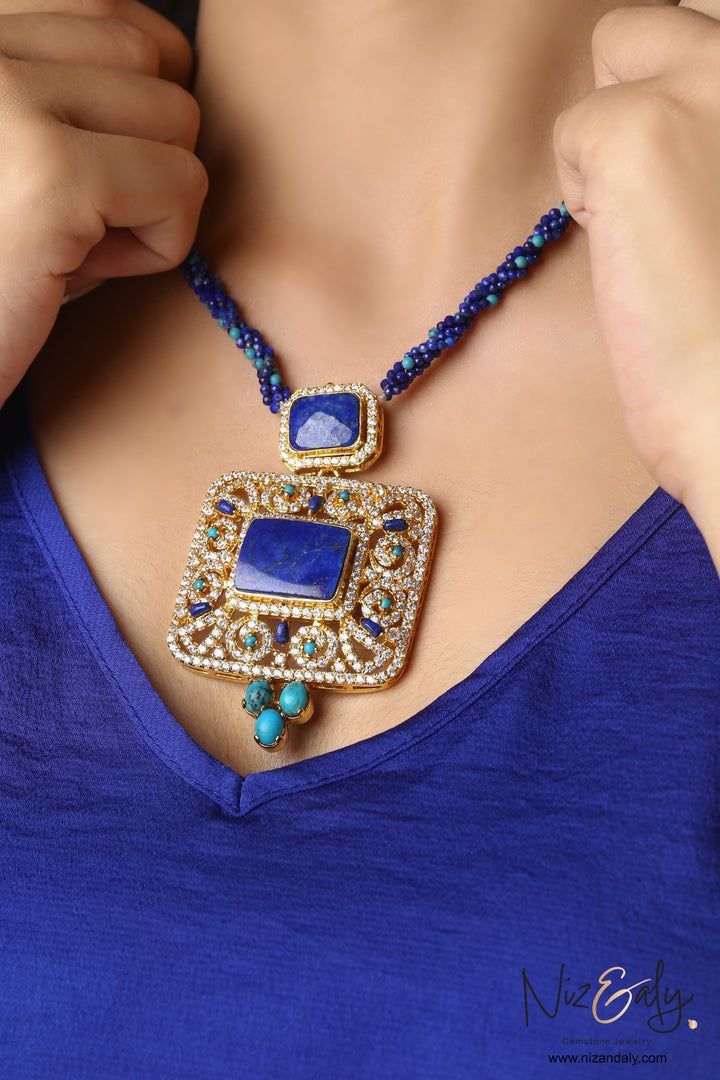 Niz & Aly Blue Monarch statement necklace featuring a square lapis lazuli pendant, turquoise accents, and gold frame.