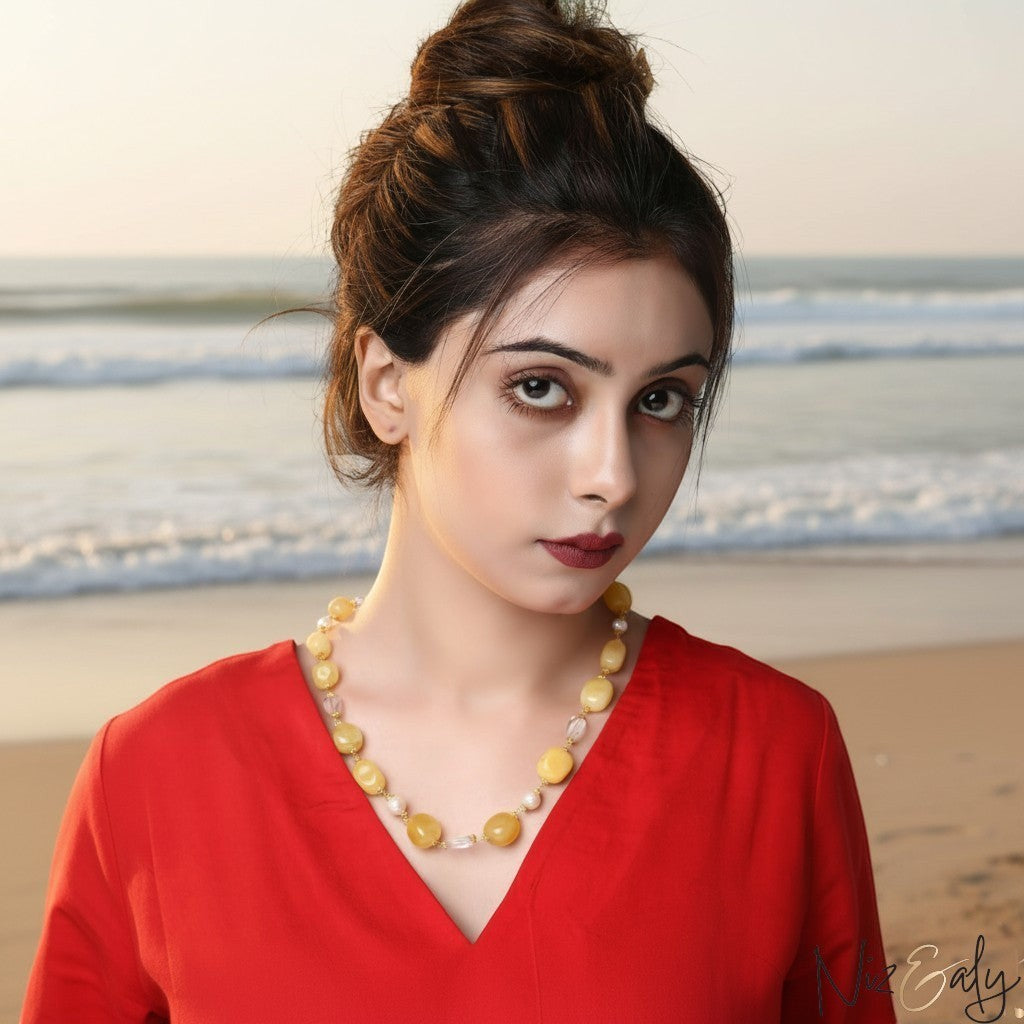 Niz & Aly lemon chiffon jade, icy quartz, and freshwater pearl beaded necklace worn by a woman on a beach.