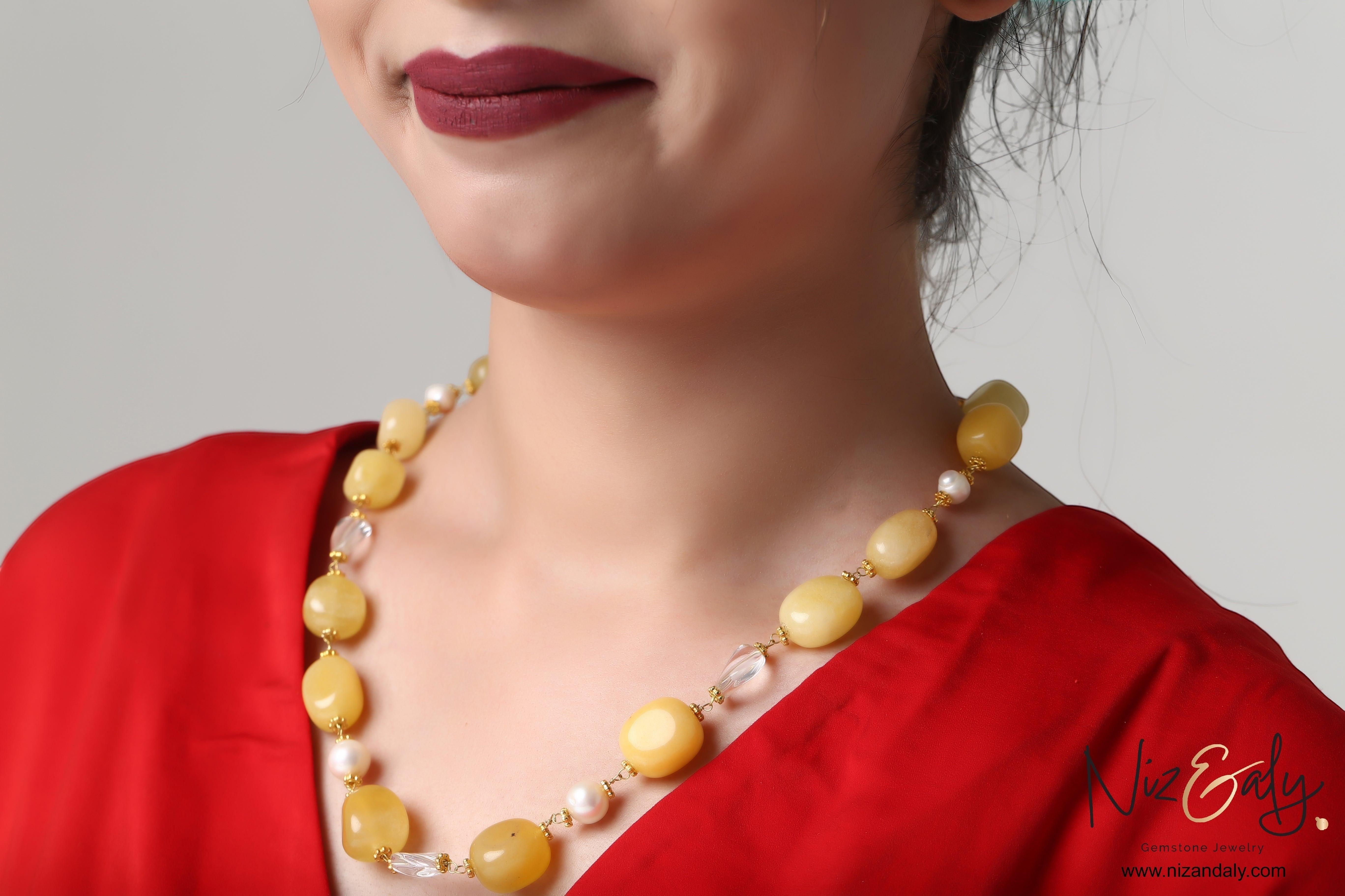 Niz & Aly lemon chiffon jade, icy quartz, and freshwater pearl beaded necklace worn by a woman in a red top.