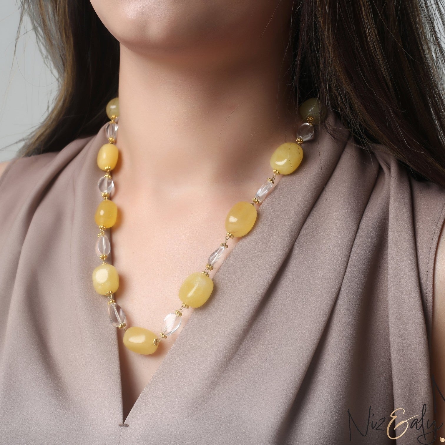 Niz & Aly handcrafted necklace featuring lemon chiffon jade and clear icy quartz beads on a woman wearing a taupe top.