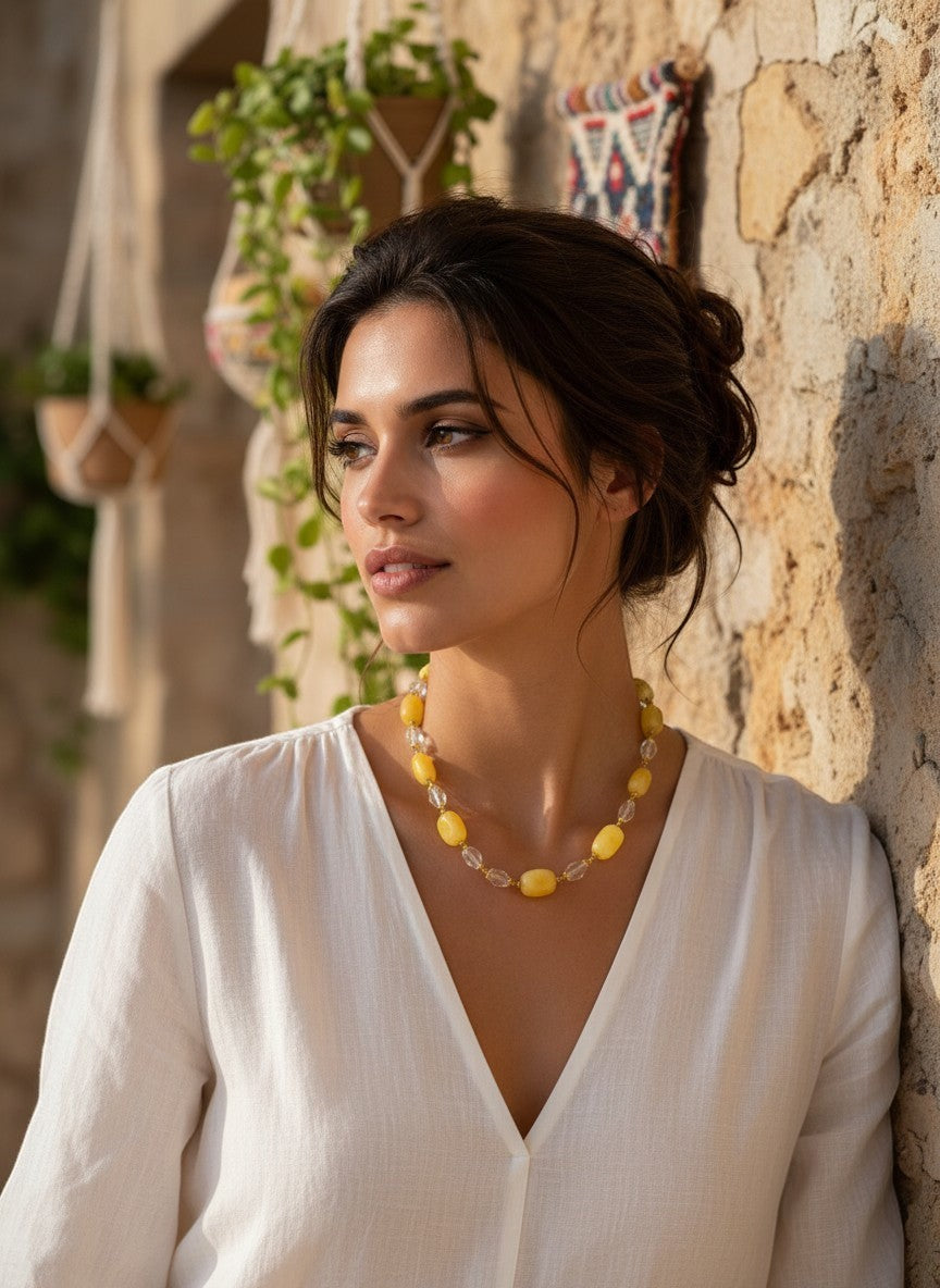 A woman wearing a Niz & Aly handcrafted necklace featuring lemon chiffon jade and clear icy quartz beads.