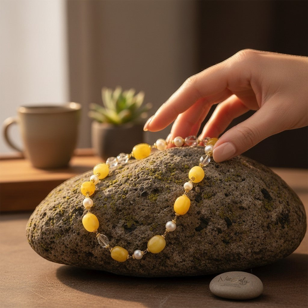 Niz & Aly lemon chiffon jade, icy quartz, and freshwater pearl beaded necklace resting on a textured stone surface.