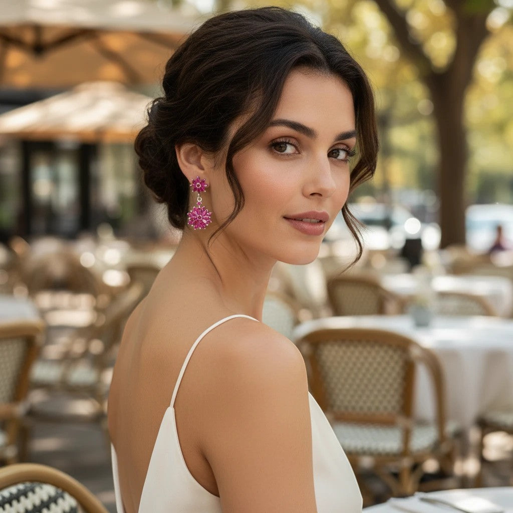 Niz & Aly marquise cut ruby drop earrings worn by a woman in a white dress at an outdoor cafe