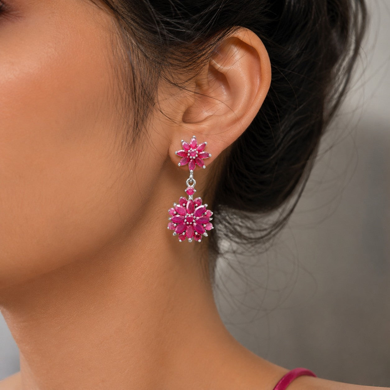 Niz & Aly marquise cut ruby drop earrings featuring floral clusters in a deep red hue worn on a model's ear