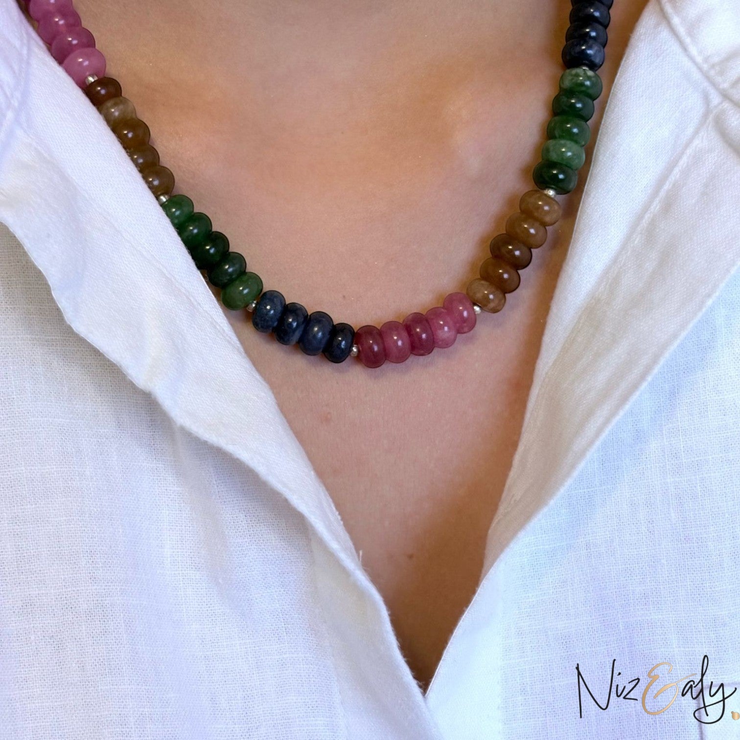 Niz & Aly multicolored oval jade quartz gemstone necklace worn on a person in a white collared shirt.