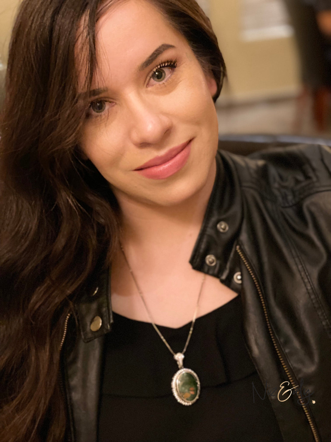 A woman wearing a Niz & Aly natural bloodstone pendant featuring deep green stone with red flecks on a silver chain.