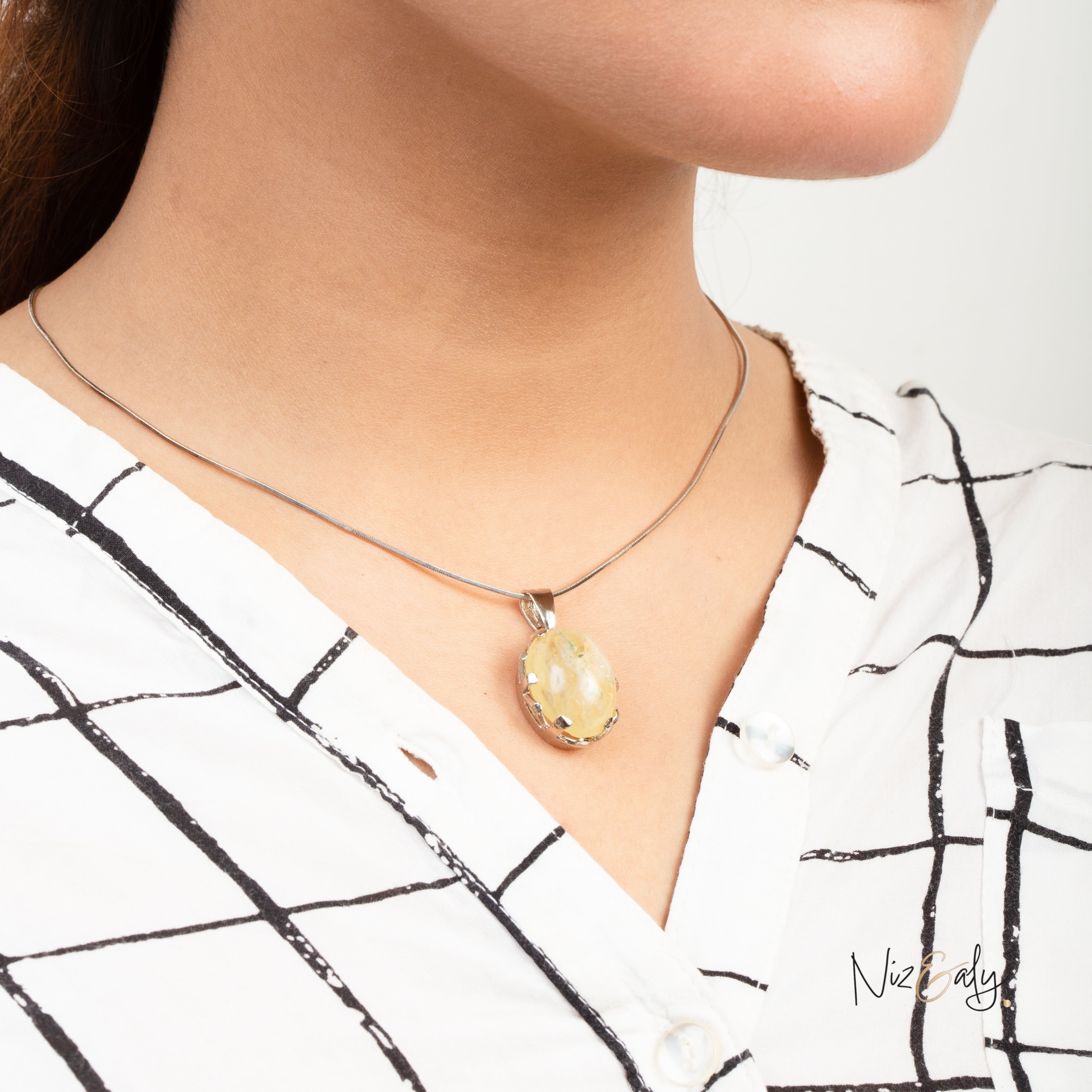 Niz & Aly natural untreated citrine locket pendant on a silver chain worn by a woman in a white plaid shirt
