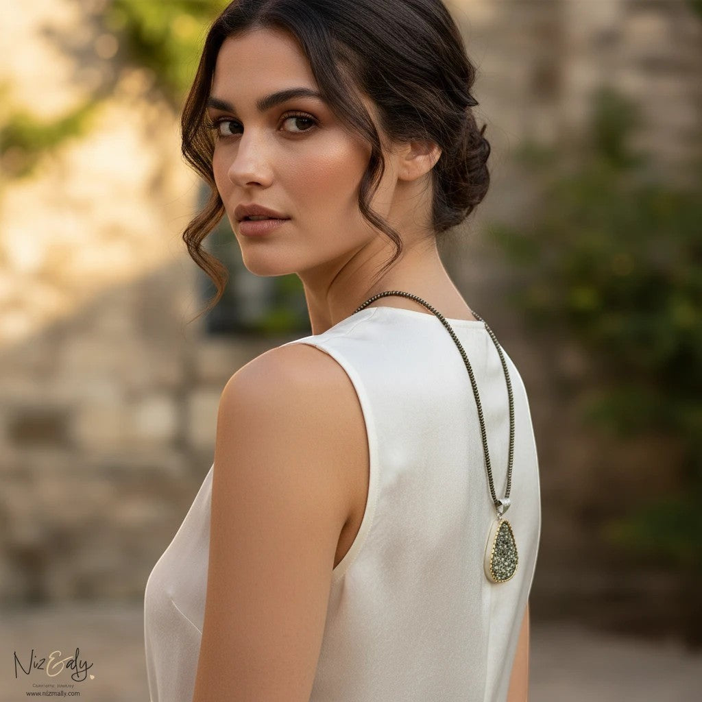 Niz & Aly natural pyrite pendant necklace with faceted beads worn by a woman in a white top, metallic gold luster.