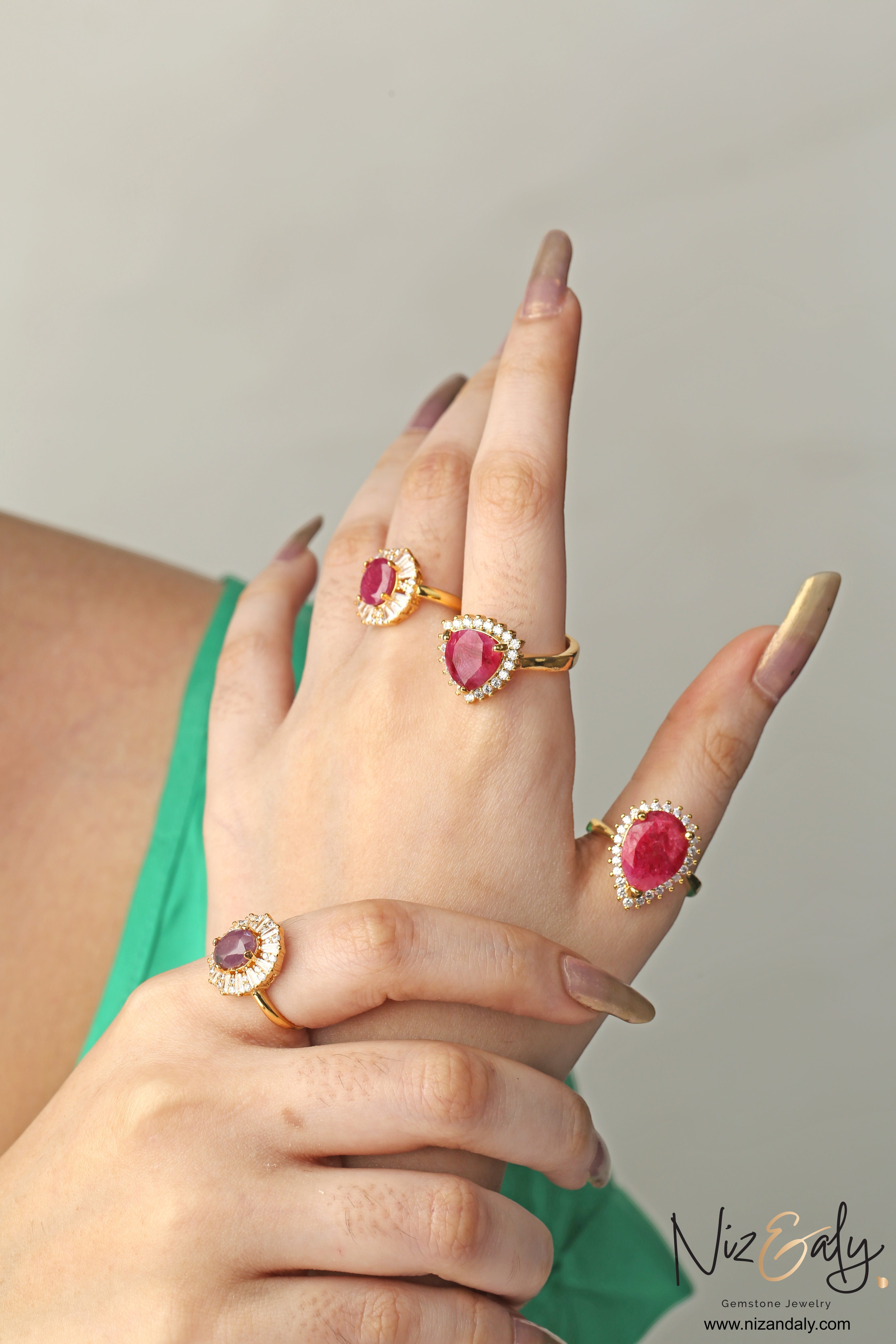 Niz & Aly natural ruby rings featuring various gemstone cuts set in gold bands with diamond halos on a woman's hand.