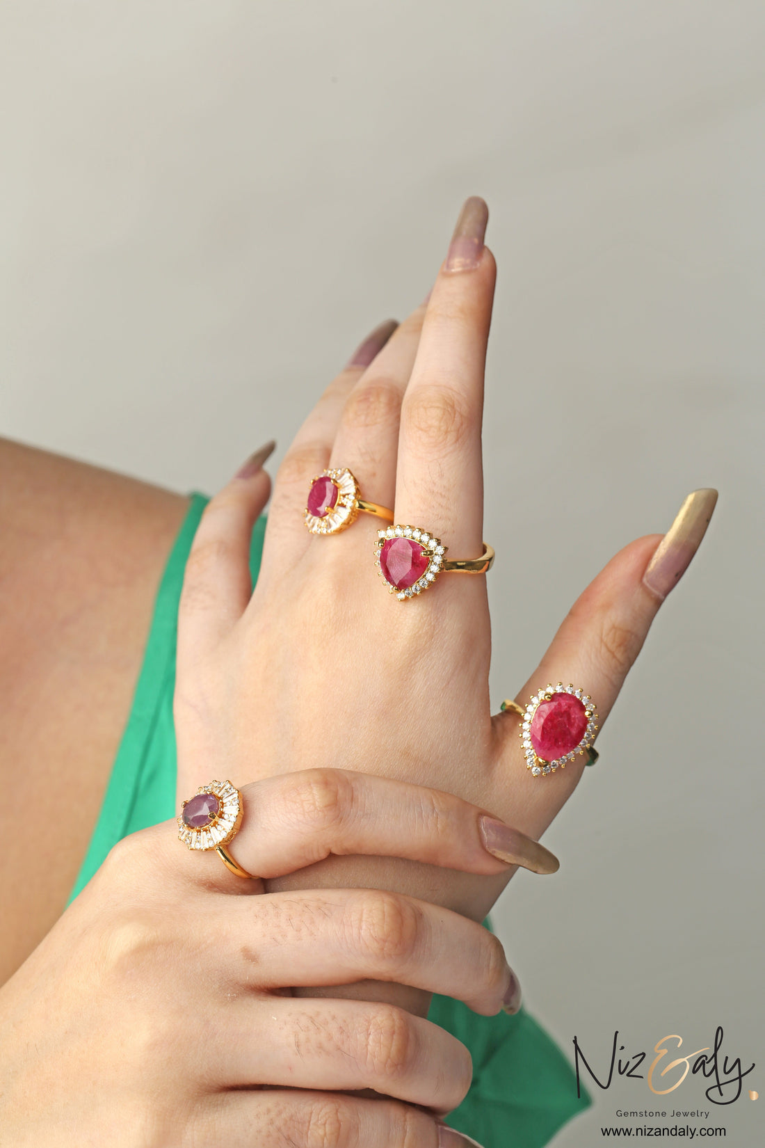 Niz & Aly natural ruby rings featuring various gemstone cuts set in gold bands with diamond halos on a woman's hand.