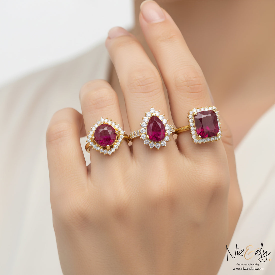 Niz & Aly natural ruby rings featuring round, pear, and cushion cuts with diamond halos on gold bands worn on fingers