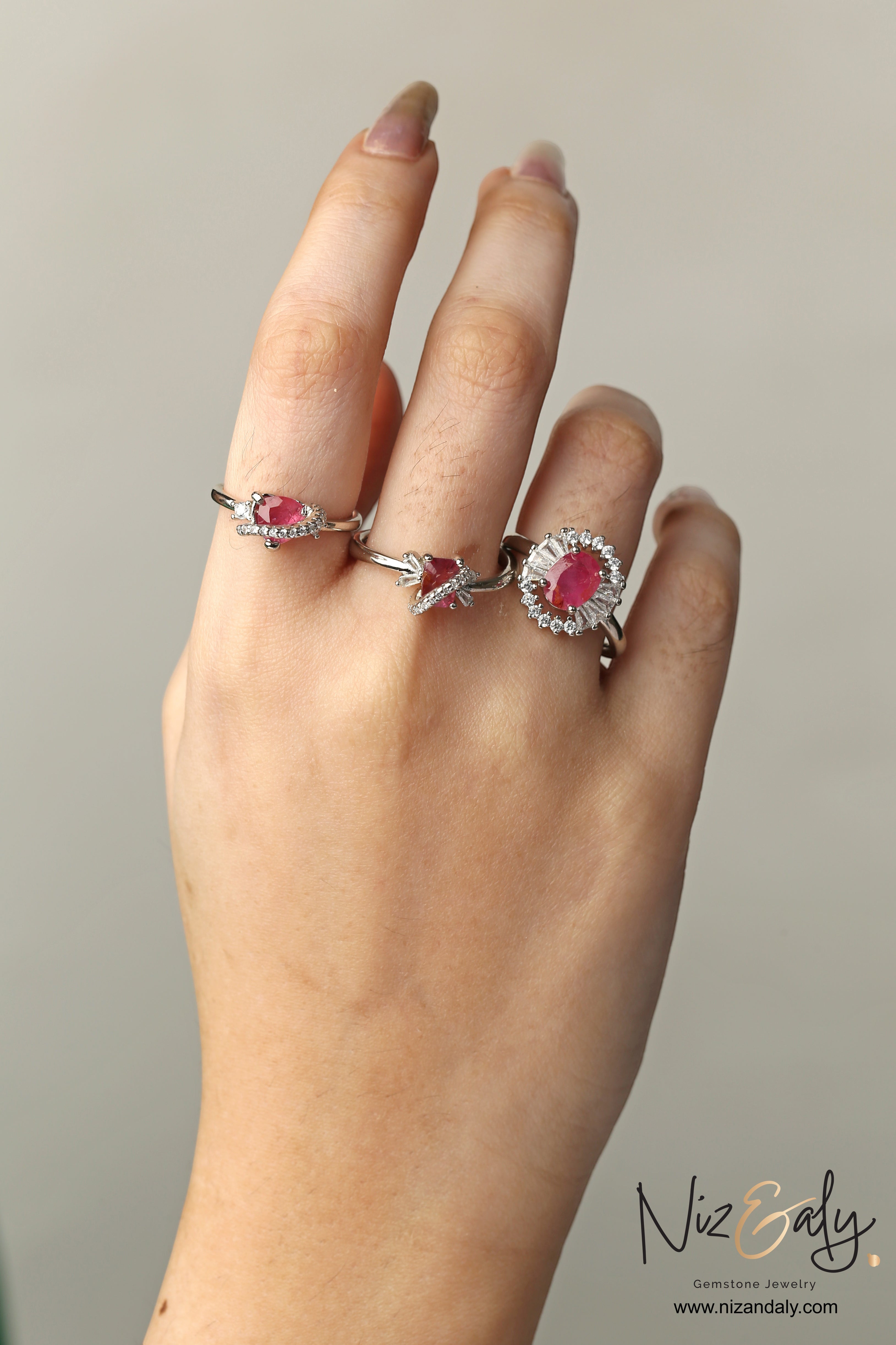 Niz & Aly natural ruby rings featuring oval and pear-cut crimson gemstones set in silver bands on a woman's hand.