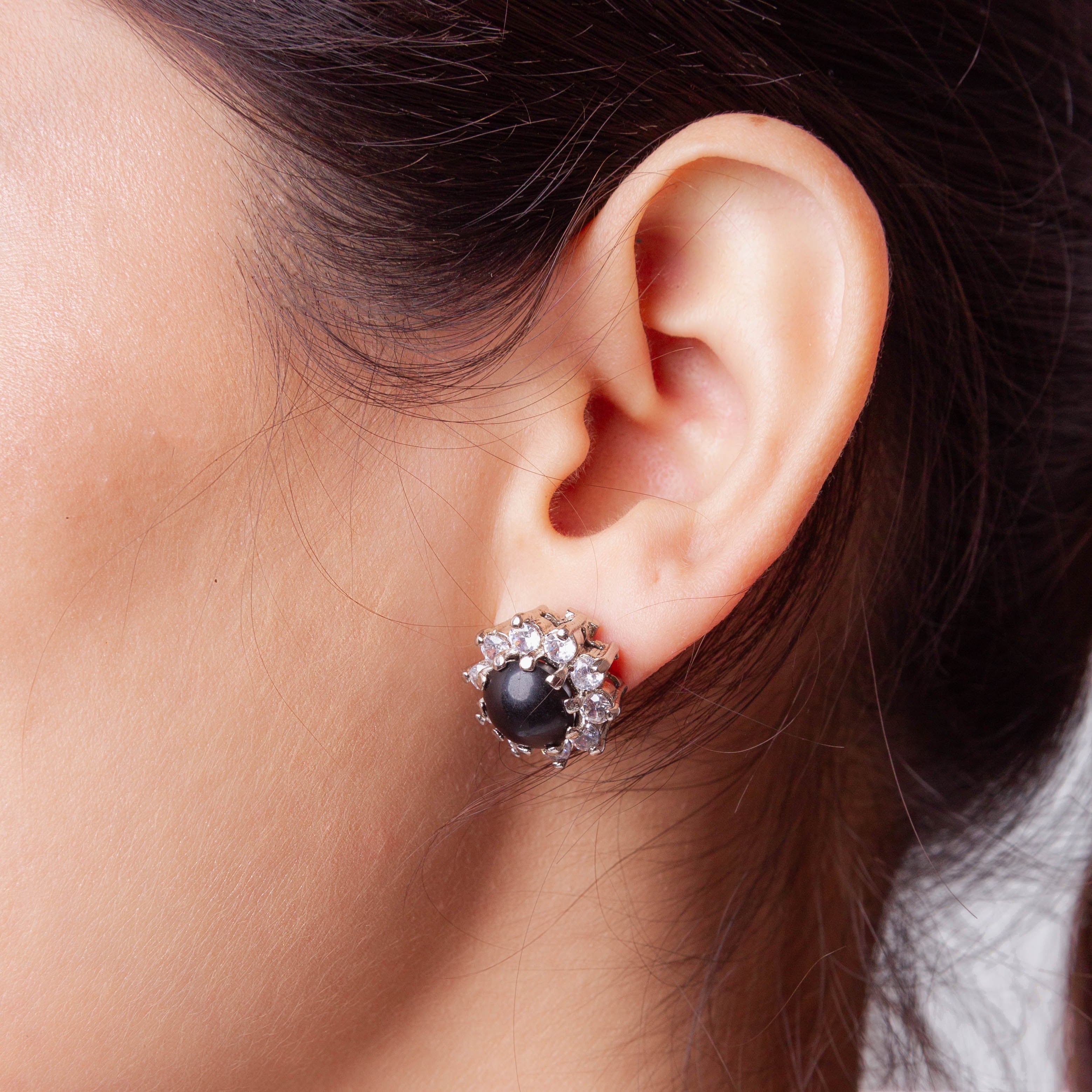Niz & Aly black onyx stud earring surrounded by sparkling clear crystals worn on a woman's earlobe
