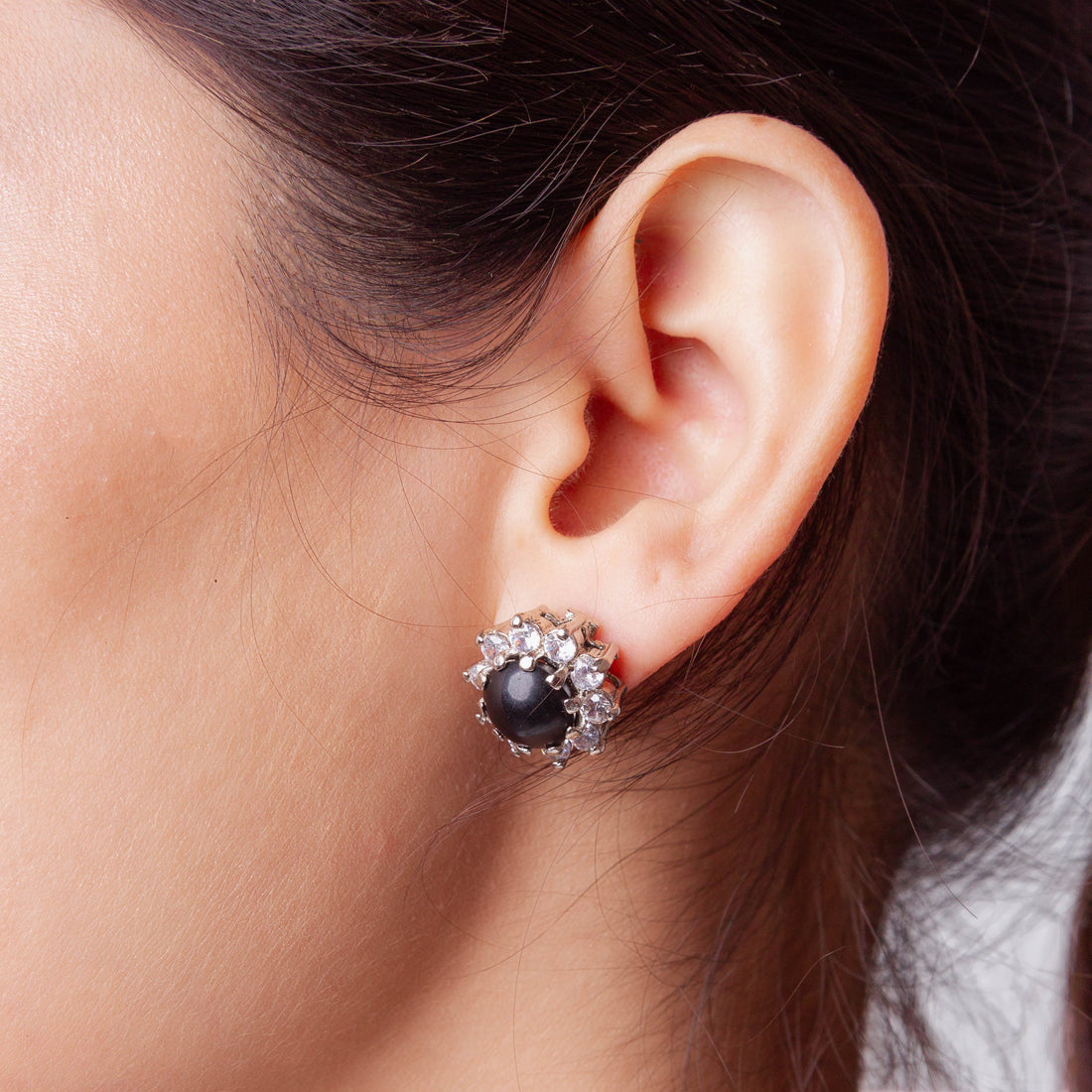 Niz & Aly black onyx stud earring surrounded by sparkling clear crystals worn on a woman's earlobe