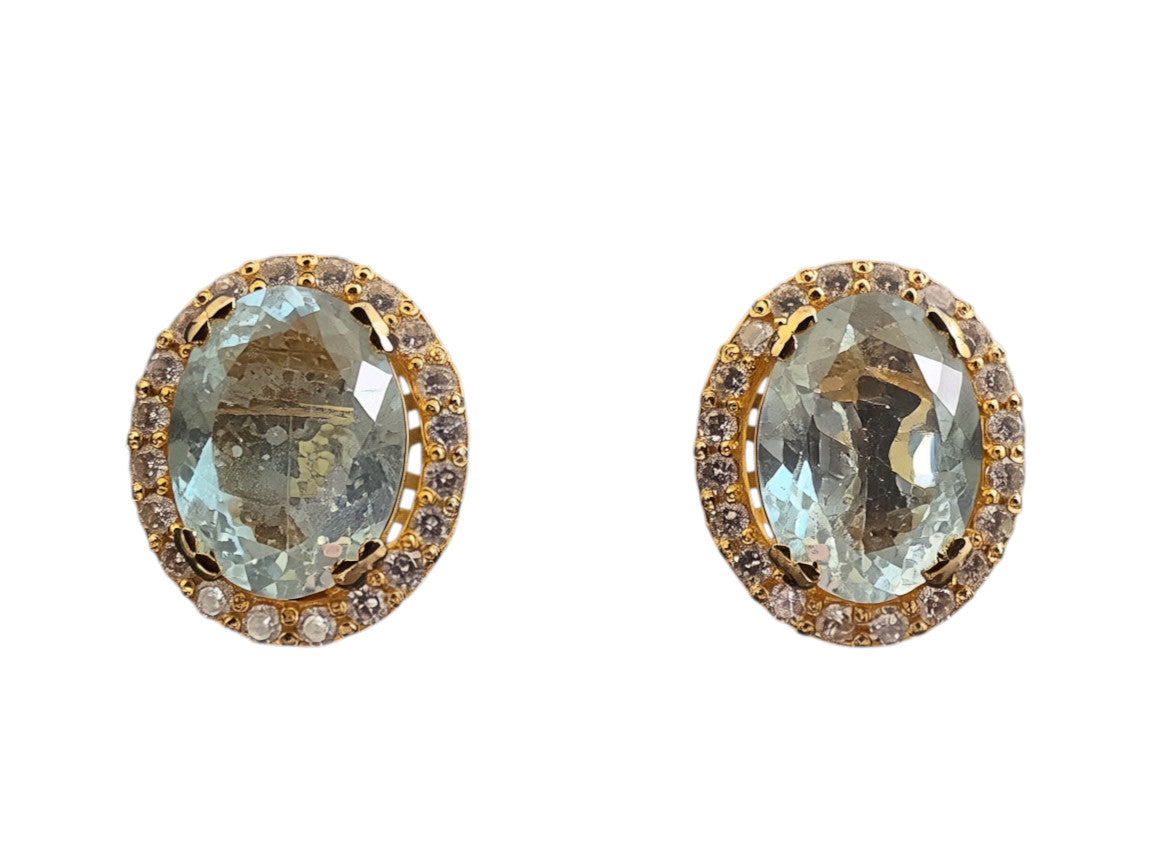 Niz & Aly oval aquamarine stud earrings featuring a gold halo setting with sparkling white accent stones.