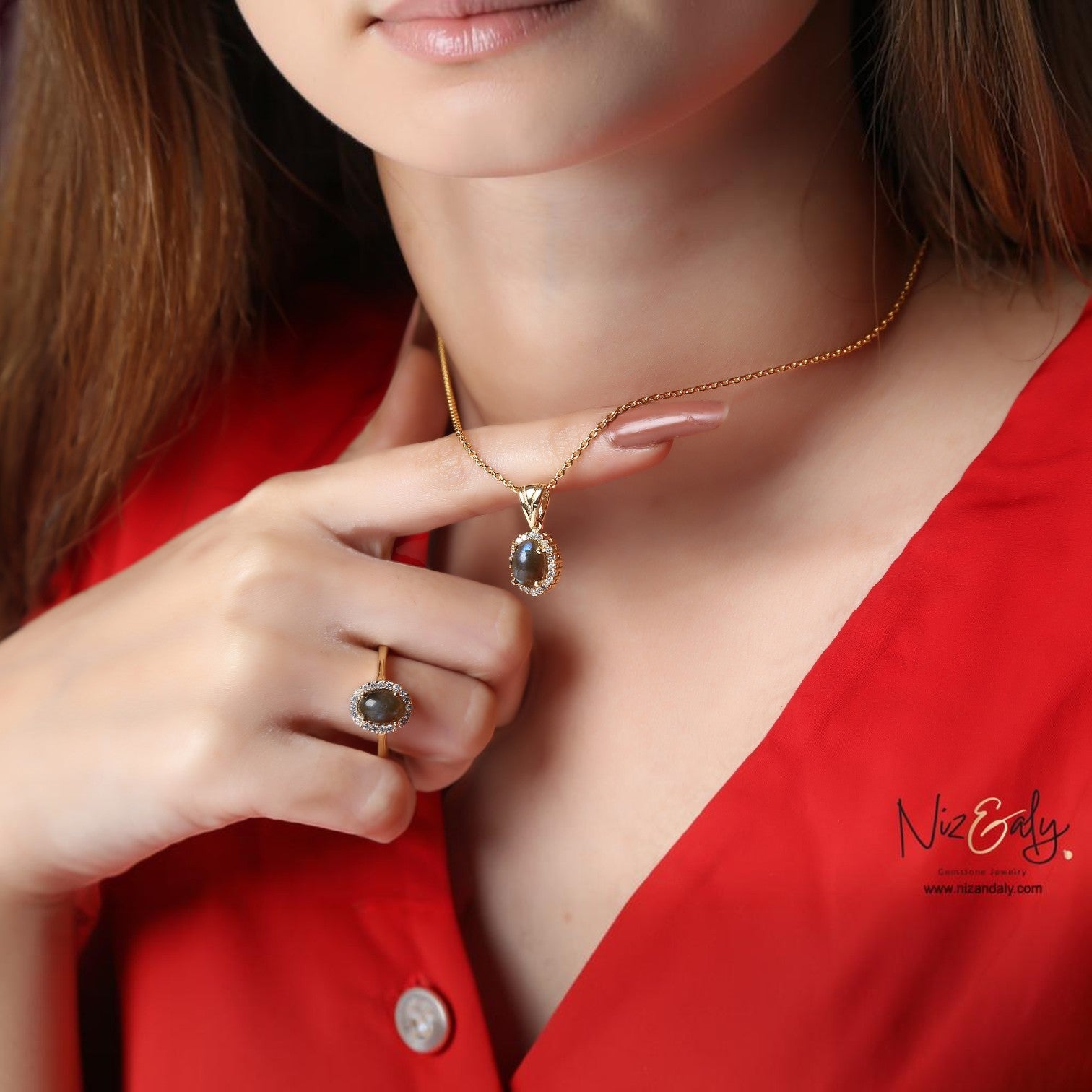 Niz & Aly dainty oval fire labradorite pendant and ring set in gold-plated 925 silver worn by a woman in a red top.