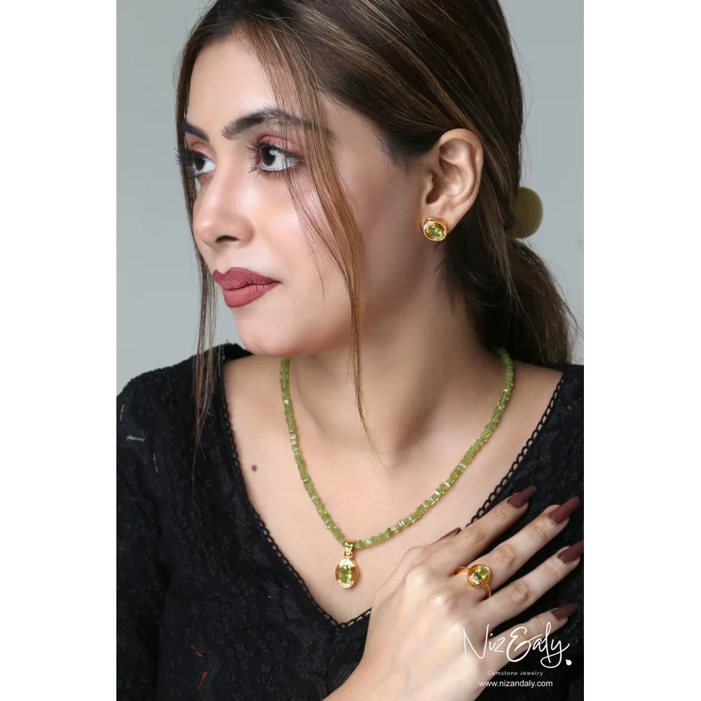 Niz & Aly oval Arizona peridot pendant set with matching earrings and ring in gold-plated sterling silver on a model.