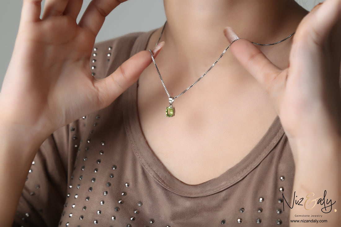 Niz & Aly oval-cut peridot solitaire pendant on a silver chain worn by a woman in a brown embellished top