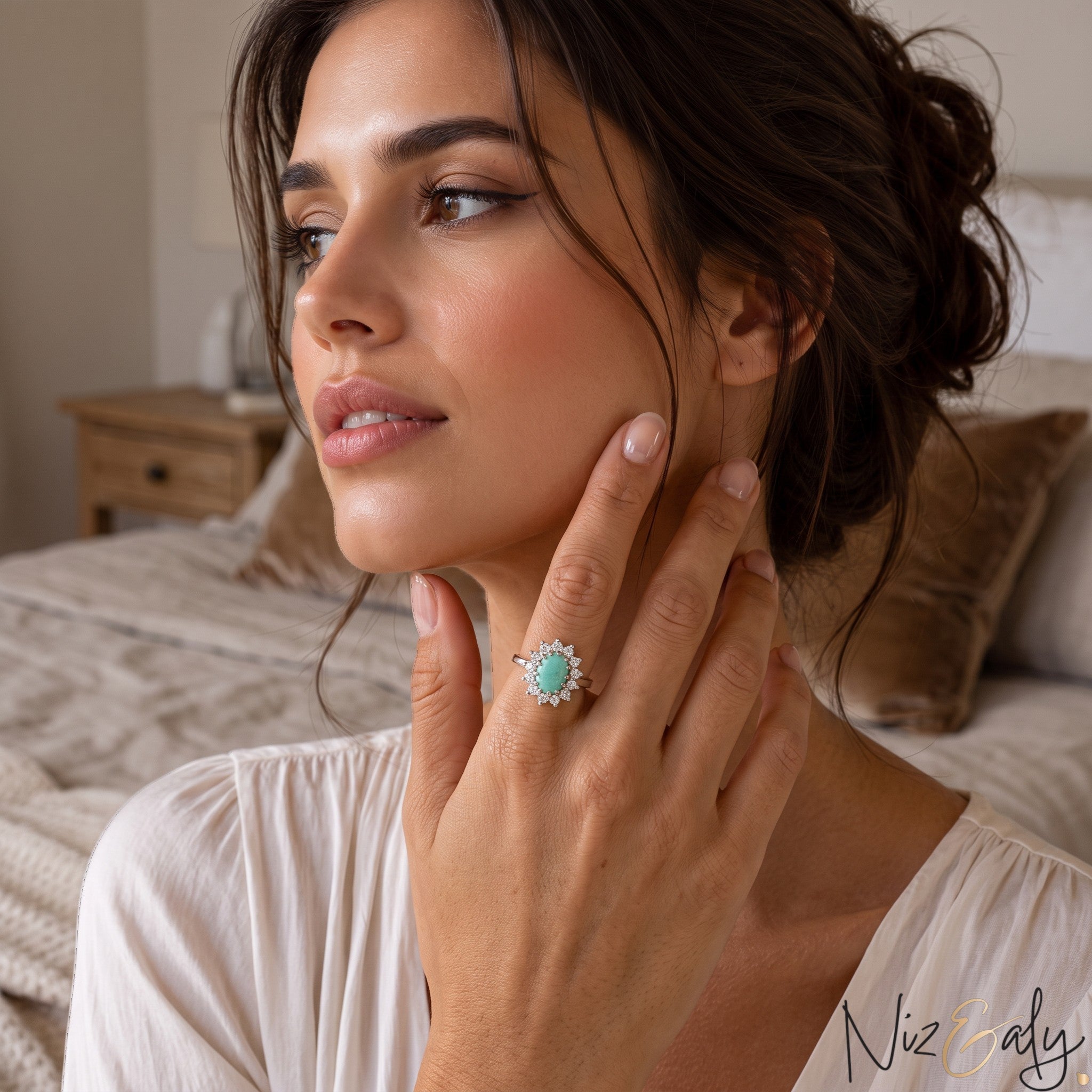 Niz & Aly oval Persian turquoise ring with a halo of small diamonds worn by a woman in a soft bedroom setting.