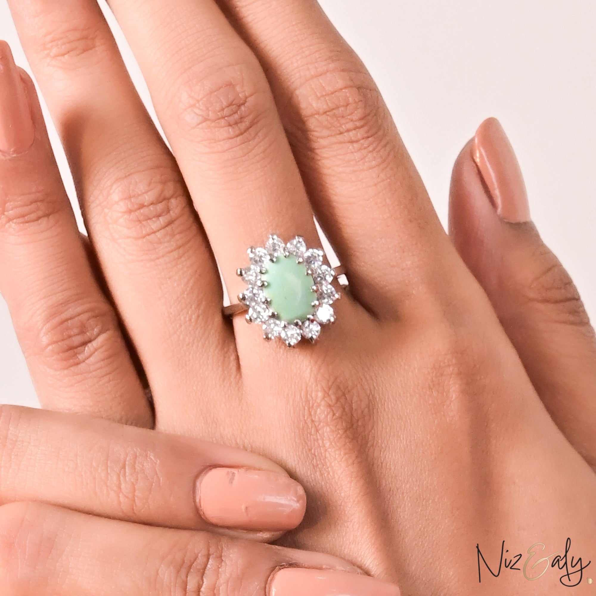 Niz & Aly oval Persian turquoise ring with a halo of sparkling white stones on a model's finger.