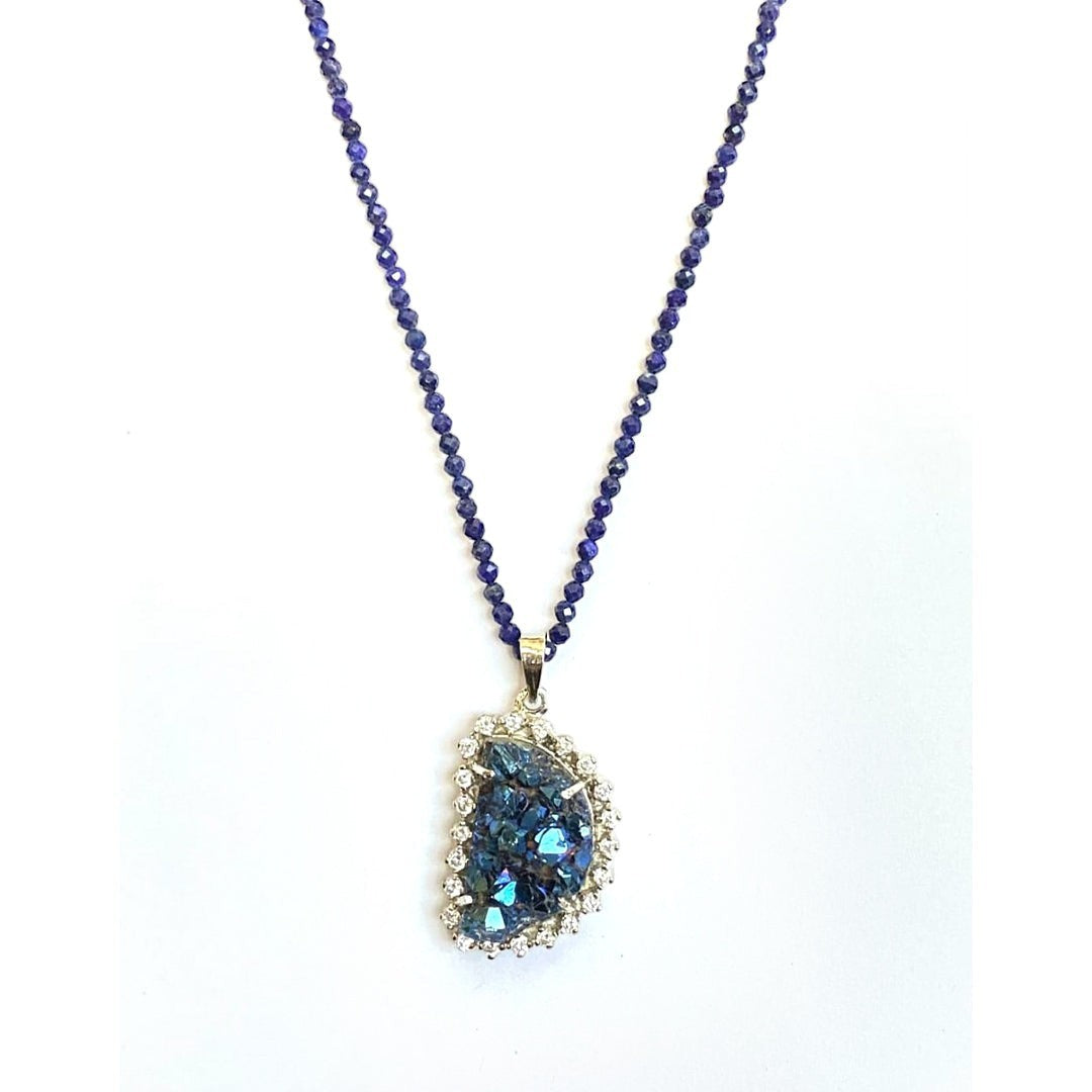 Niz & Aly peacock ore bornite pendant on a strand of faceted blue lapis lazuli beads with a crystal-accented setting.