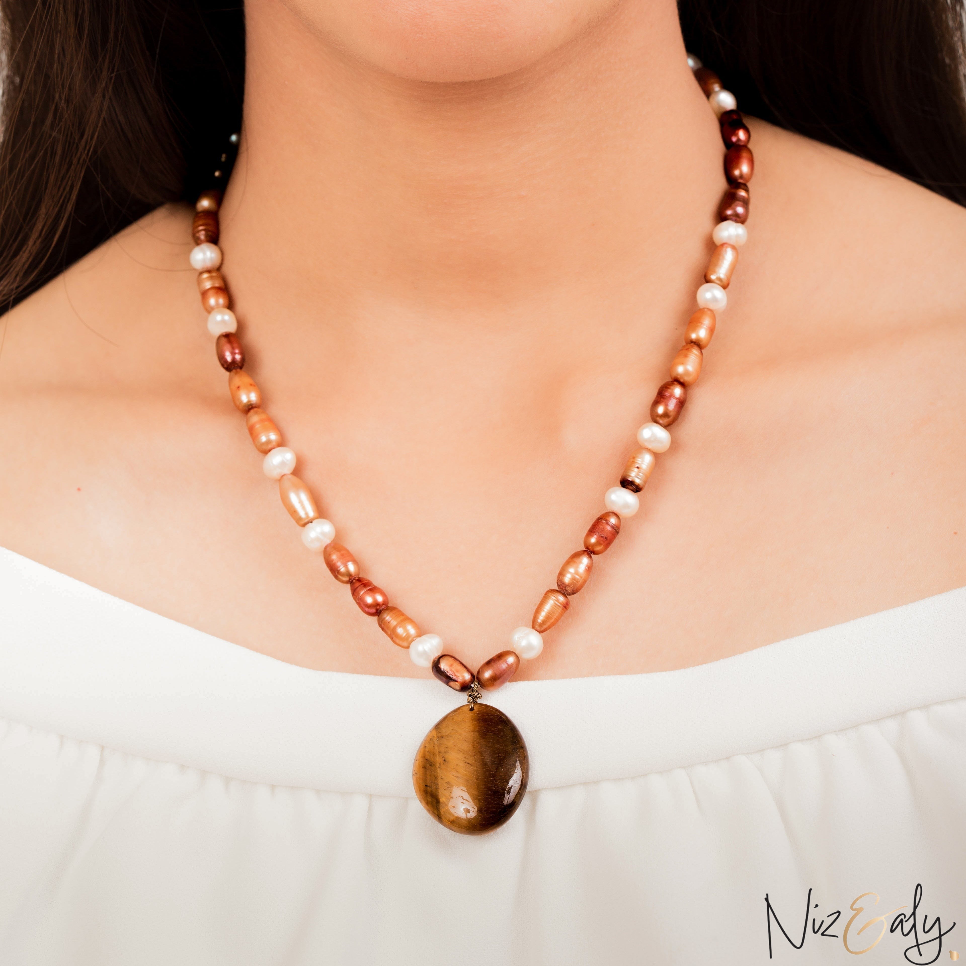 Niz & Aly necklace featuring iridescent freshwater pearls in brown and white tones with a polished tiger eye pendant