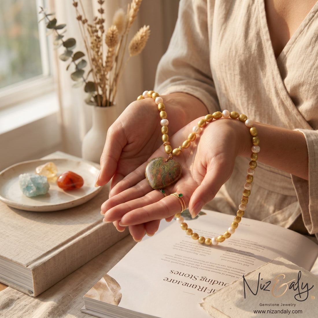 Niz & Aly cultured pearl necklace featuring a natural green and brown unakite heart pendant held in hands.