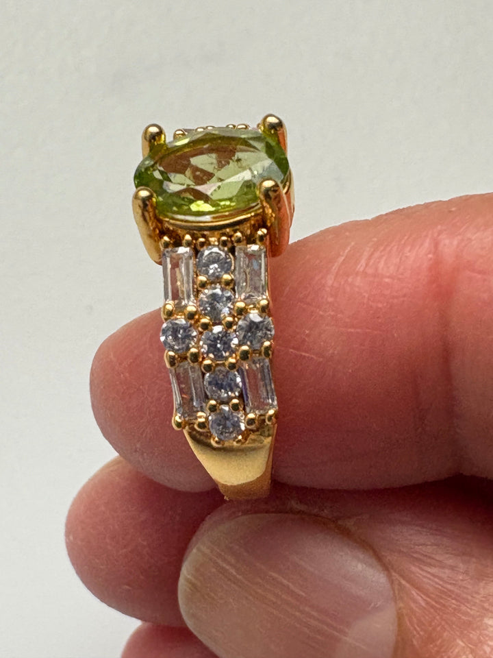Niz & Aly natural apple green peridot ring with gold plating and sparkling cubic zirconia accents on a finger