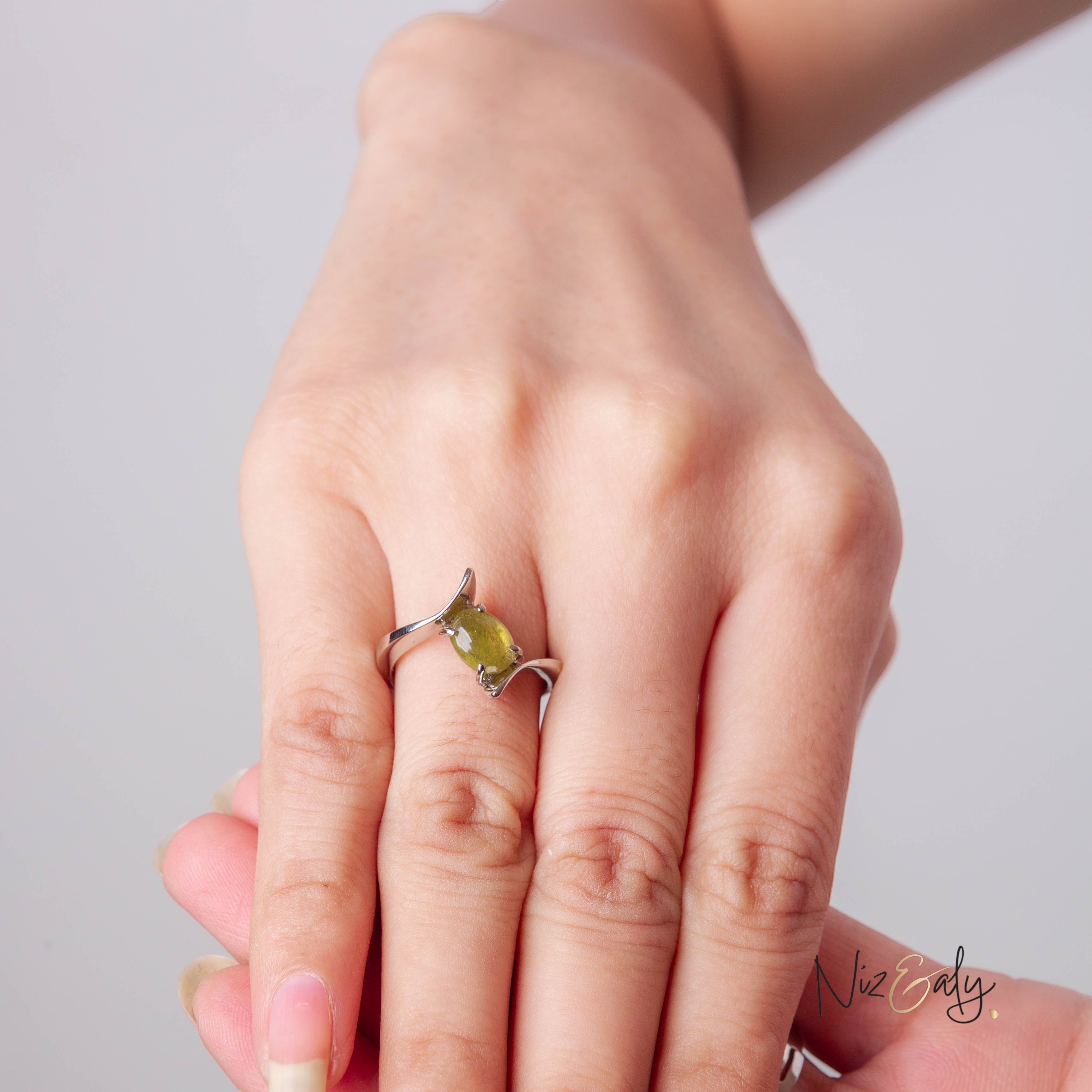 Niz & Aly sterling silver statement ring featuring an oval-cut olive-green peridot gemstone in a modern bypass design.