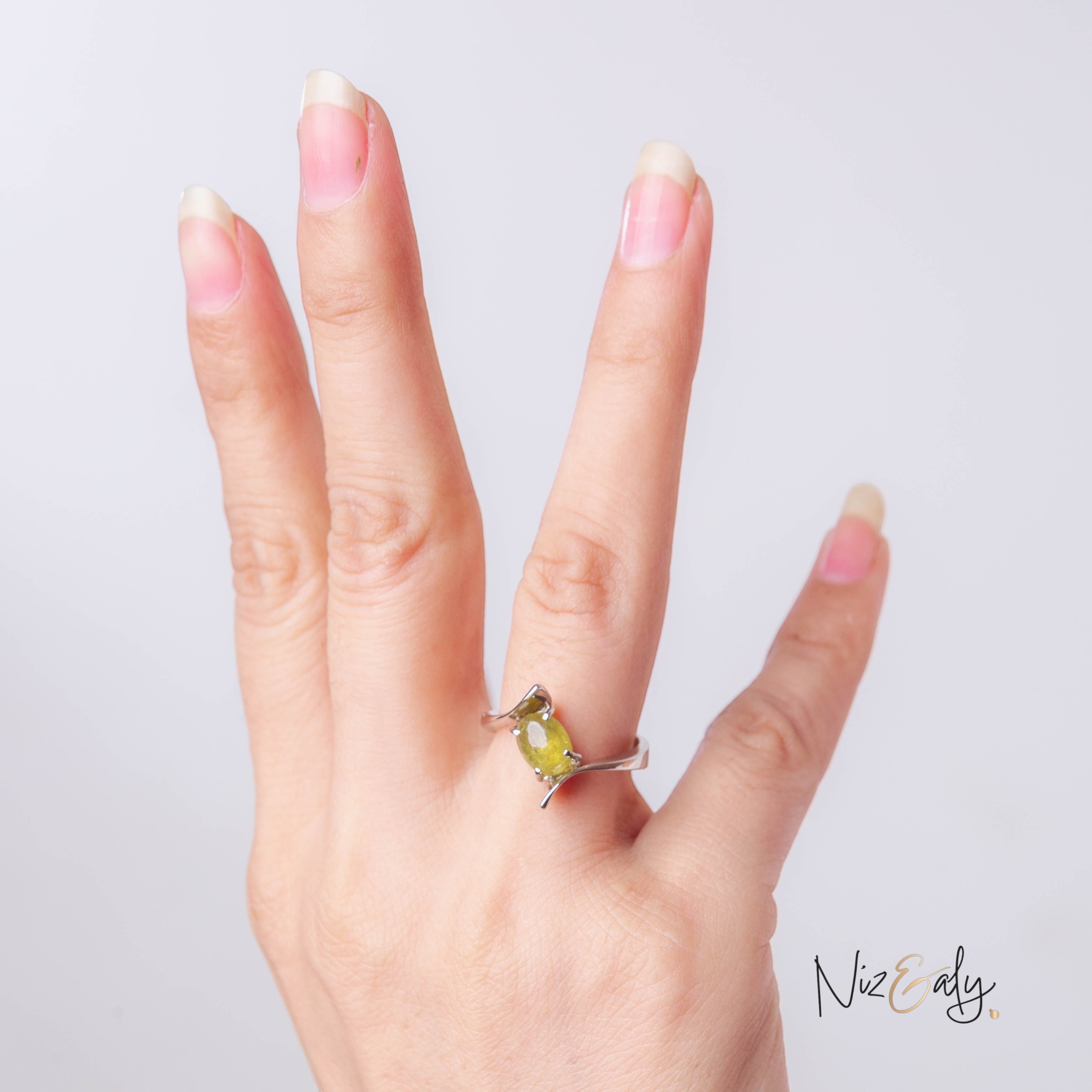 Niz & Aly sterling silver bypass ring featuring an oval-cut olive-green peridot gemstone worn on a woman's finger.