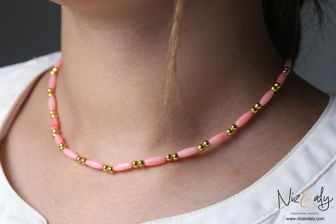 Niz & Aly dainty pink rice-shaped coral necklace with gold beads worn on a model against a neutral background.