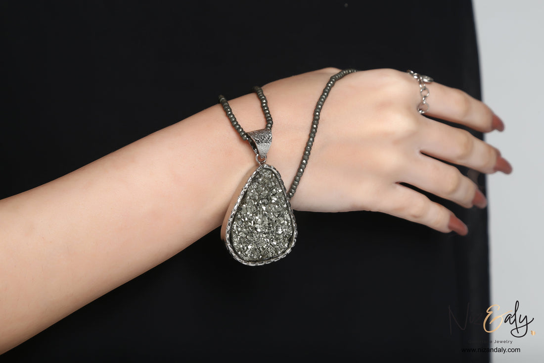 Niz & Aly oval natural pyrite pendant on a faceted pyrite beaded strand worn on a model's wrist