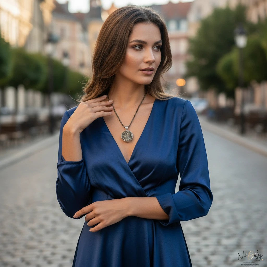 Niz & Aly round pyrite pendant necklace worn by a woman in a blue dress on a cobblestone street.