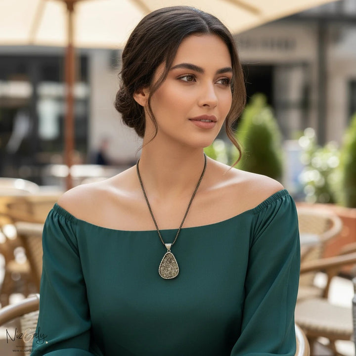Niz & Aly oval natural pyrite pendant on a faceted pyrite beaded necklace worn by a woman in a green top