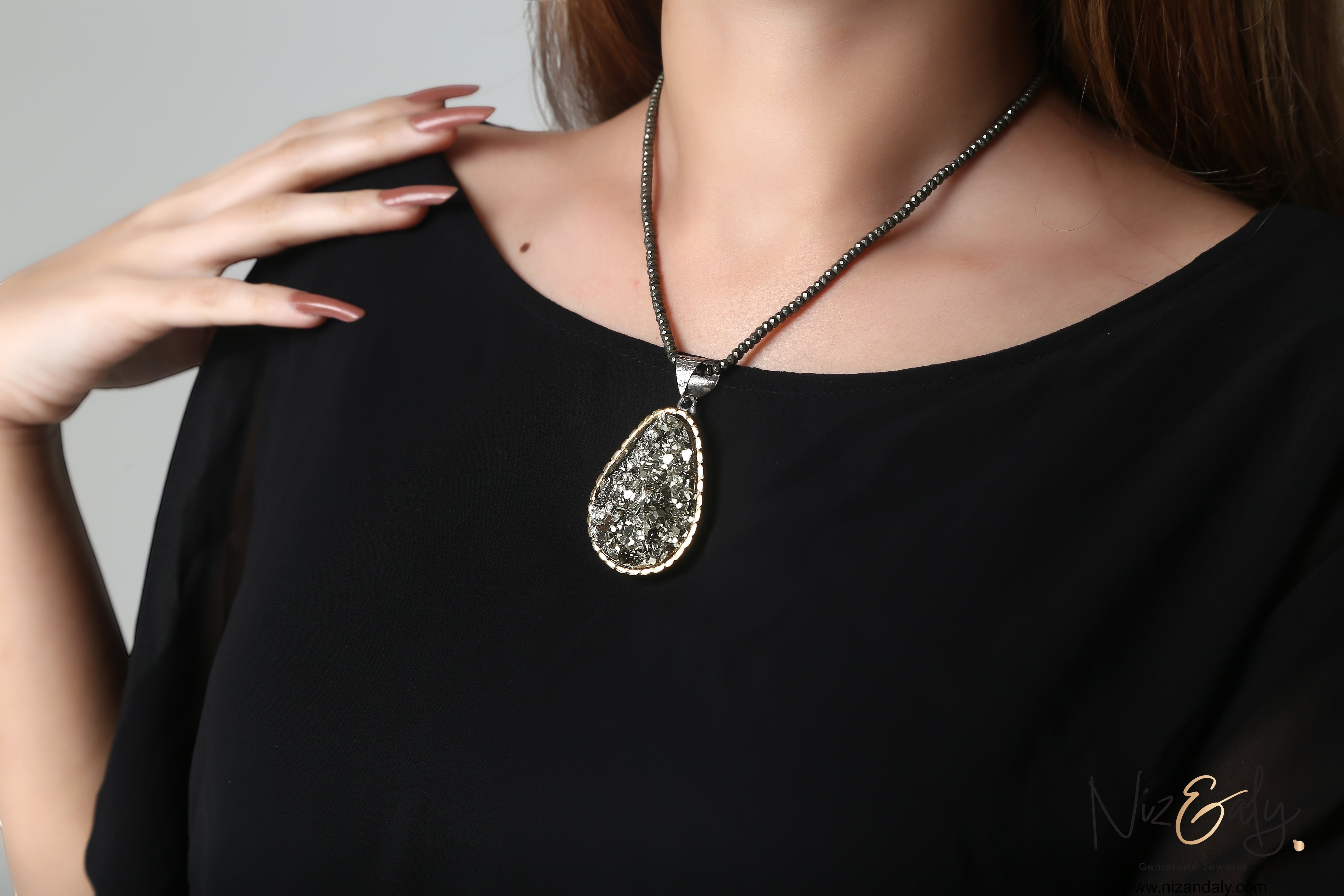 Niz & Aly natural pyrite pendant necklace featuring a faceted pyrite bead chain on a model wearing a black top.