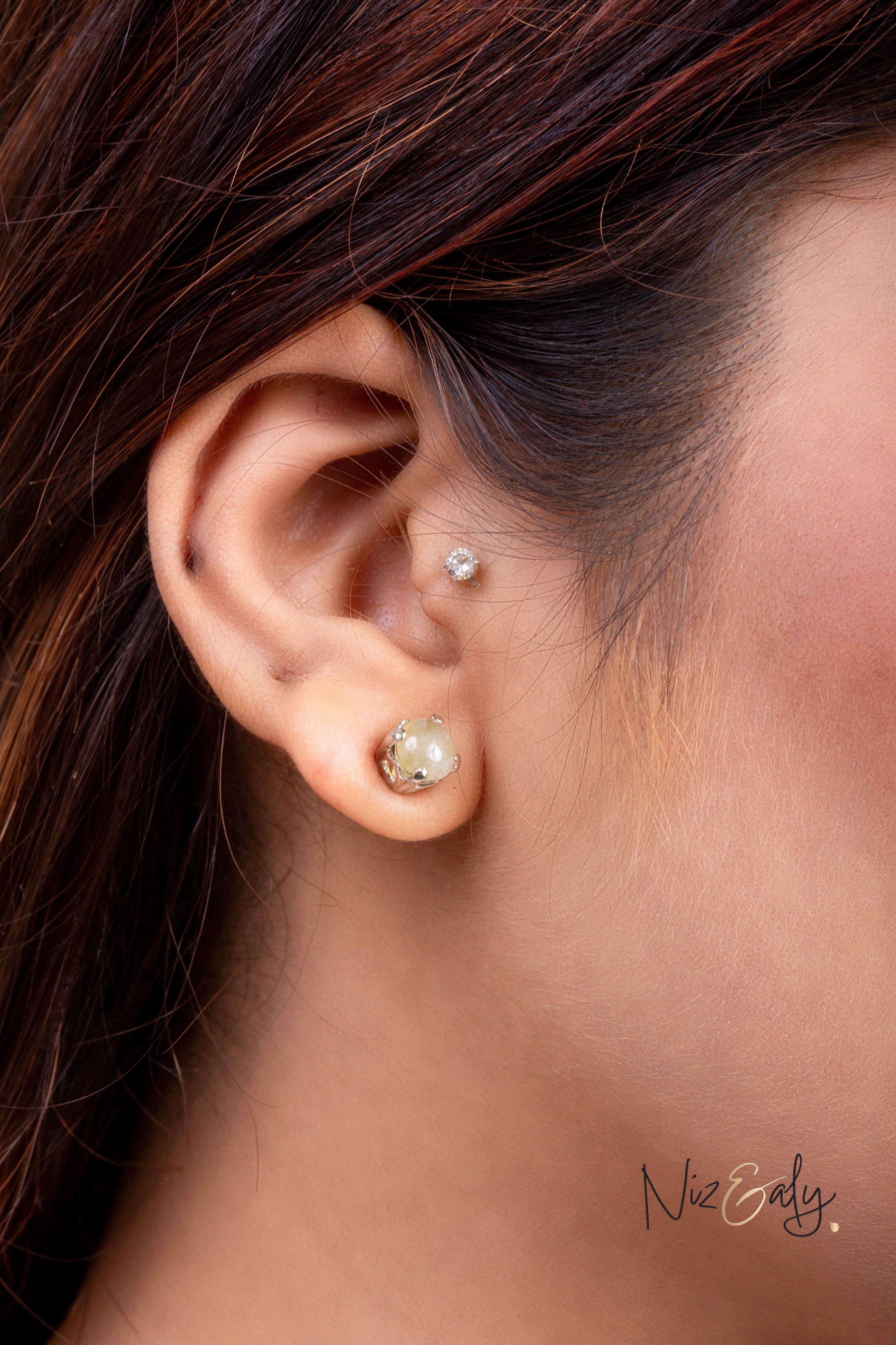 Niz & Aly Raw Citrine Bliss stud earring worn on a woman's earlobe, featuring a rough golden-yellow citrine stone.