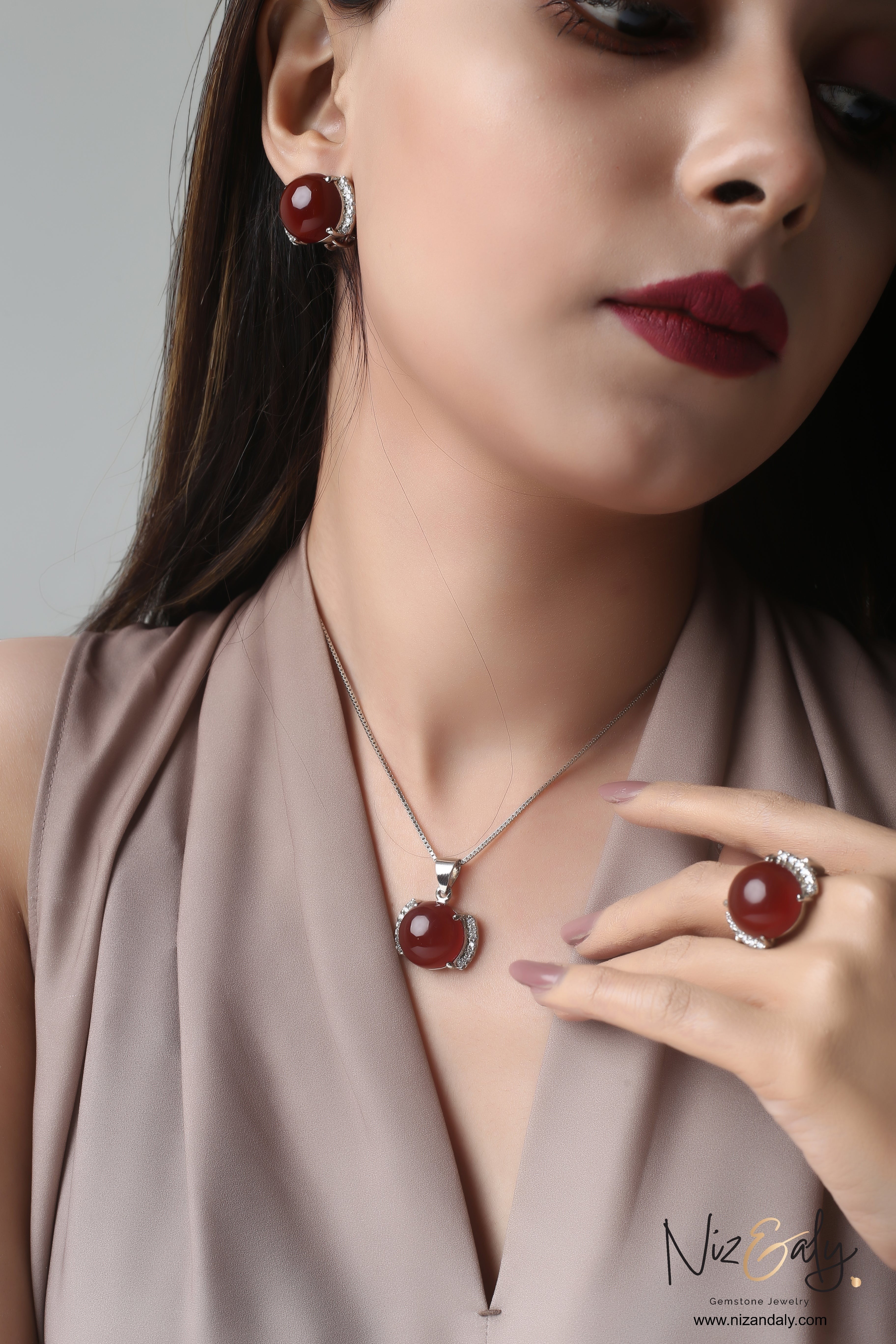 Niz & Aly red agate pendant, earrings, and ring set worn by a woman, featuring polished gemstones in silver settings.